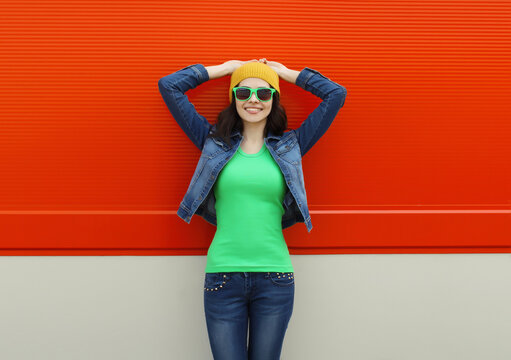 Happy smiling young woman in summer posing against colorful wall on city street