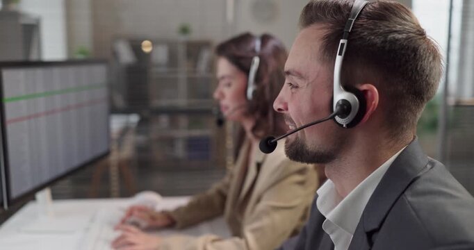 Agents with headset provide support at office computer. Operators handle calls, log tickets, and update records on dual monitors in a modern workspace. Concept shows efficient customer service.