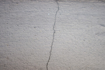 Fototapeta premium Cracked concrete wall close up. Grey cement surface with visible fracture line, structural damage concept, minimal industrial background, rough texture, high resolution.
