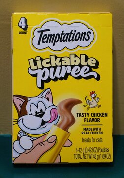 Wilmington, Delaware, U.S.A - April 10, 2026 - Yellow box of Temptations Lickable Puree cat treats featuring tasty chicken flavor and four 12-gram pouches
