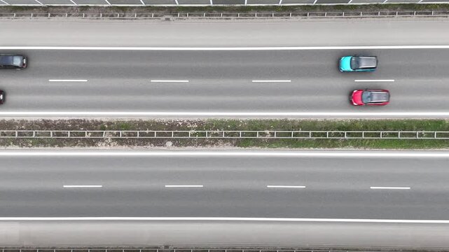 Aerial view of cars and a truck traveling at high speed on a multi-lane highway, showcasing the dynamic flow of traffic and road infrastructure in a modern urban setting