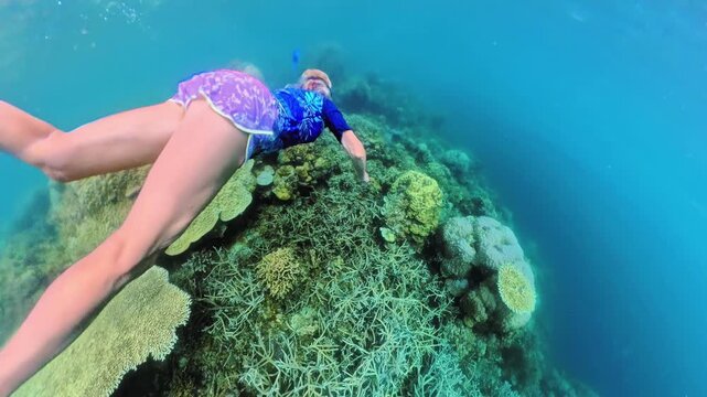 woman wearing diving mask and snorkel swimming over vibrant coral reef formations, exploring clear blue underwater world during a tropical summer vacation in Port Barton, Philippines, Palawan island