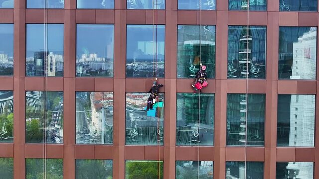 Aerial Poland window washers on high rise building close 2. Historical capital Greater Poland. Academic, scientific, cultural center. Metropolitan area with modern high rise business and apartments.