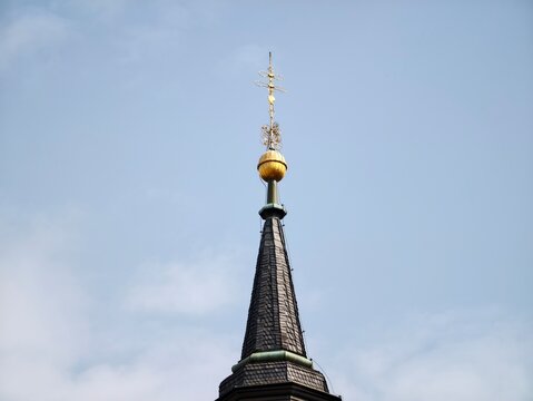 Church spire elegance. Serene image of traditional church spire with gilded symbols against soft sky