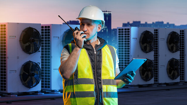 HVAC maintenance, Climate control service. Technician with radio and tablet inspects rooftop air conditioning units, coordinating diagnostics and system operation.