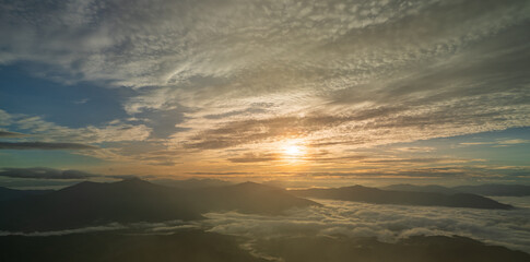 Fototapeta premium Beautiful sunrise sky with golden light over misty mountains and soft clouds in the valley.