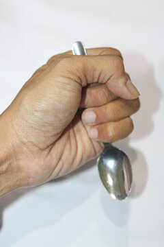 Hand grips spoon tightly against white background