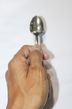 Hand grips spoon against a clean white background