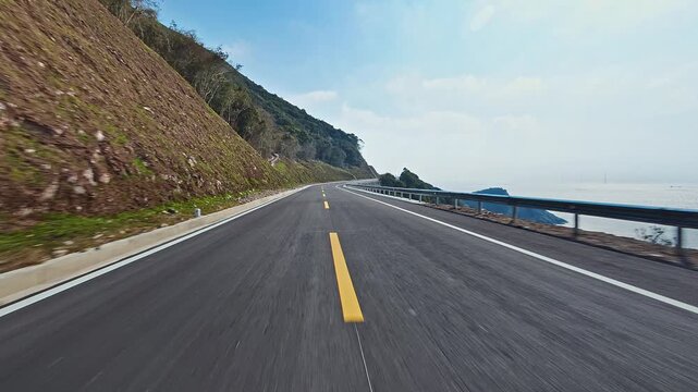 Scenic coastal asphalt road with yellow line winding through green mountains and blue sea