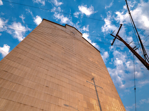 Power poles casting shadows on the corrugated metal wall of an old grain elevator in early morning