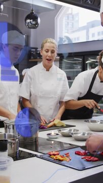 Vertical video: Chef speaking showing pepper cutting in kitchen guiding hand as blue tint obscuring