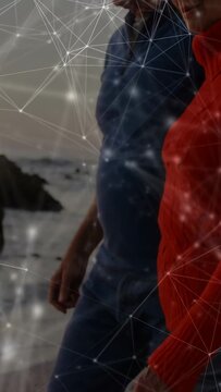 Vertical video: Two seniors walking shore as camera rises, activating node overlay showing vitals