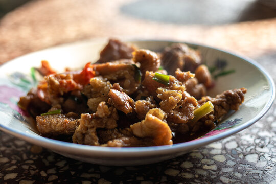 Delicious homemade Asian dish of stir-fried hot meat with green scallions and chili served on a vintage floral plate over a terrazzo table