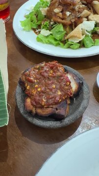 pecak cucut is a traditional Indonesian dish from Pekalongan, made with smoked or fried shark, served with spicy red sambal of chili, shrimp paste, tomato, and shallots, creating a rich, tender flavor