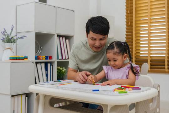 Caption/Description: father and child girl drawing and painting with colorful oil pastels on paper