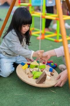 mother and preschool child girl playing with wooden toy block at outdoor
