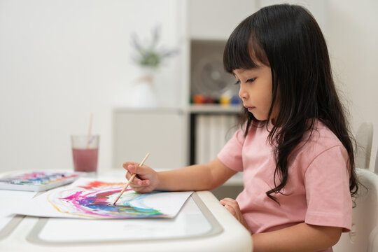 preschool child girl painting on paper with watercolor in pan