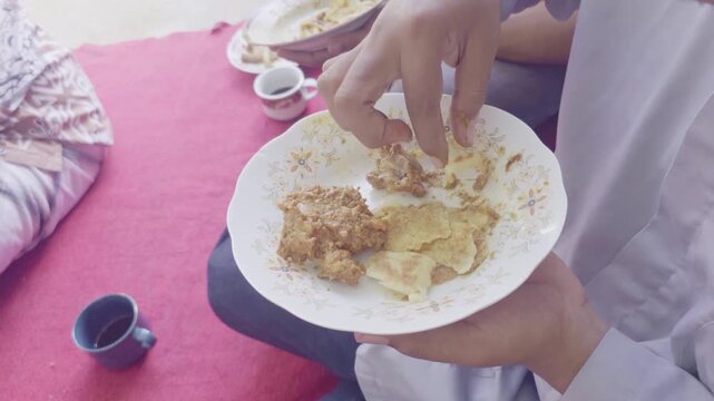 Close-up of a person eating traditional roti kambing, a local bread and goat meat dish from Southeast Maluku, Indonesia. 