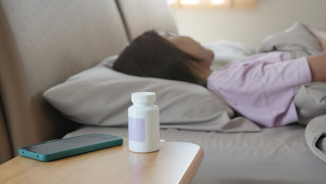 Young adult woman black asia people take herbal CBD pill bottle lying down on soft cozy bed deep sleep aid calm. Waking up happy serene relax drug anti aging good health care fall asleep till morning.