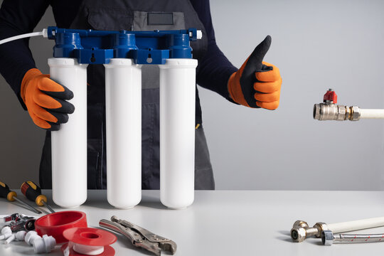 Plumber man with water filter equipment gesturing thumb up.