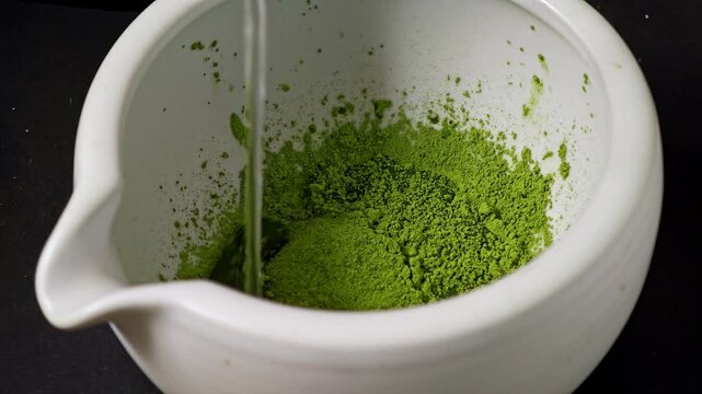 Pouring warm water into matcha powder.