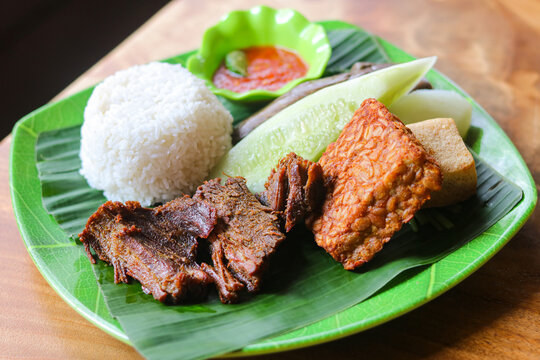 Nasi Tempong Empal. The platter features rice served alongside tender, sweet and savory fried beef, tempe, tofu, vegetables and a signature fiery red chili sambal.