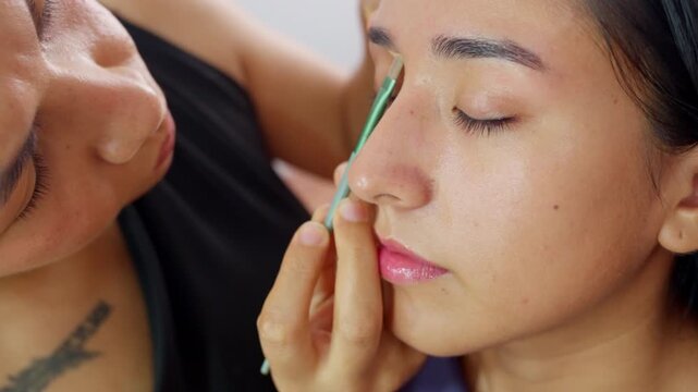 Makeup artist applying concealer on client's eyelid
