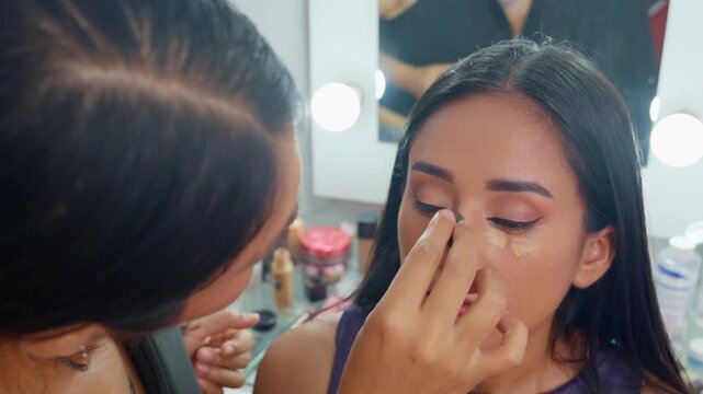 Makeup artist applying concealer to young latina woman
