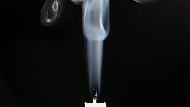 A close-up shot captures the delicate dance of smoke rising from a burning candle against a stark black background, highlighting the ephemeral nature of light and shadow.