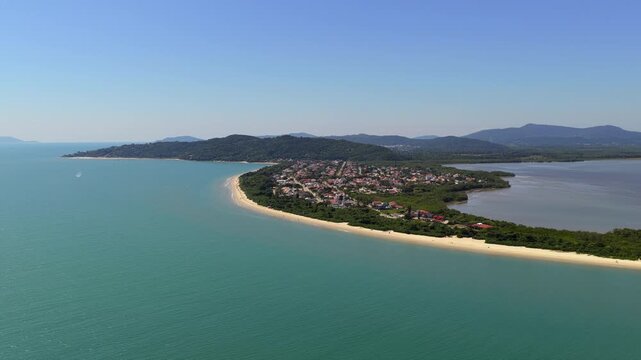 Deep blue ocean looking towards distant shores of Praia da Daniela, Florian&oacute;polis, on a clear day. Forward aerial ascent over the water.