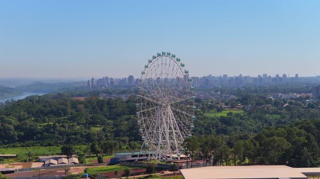 Aerial drone view of the Yup Star giant Ferris wheel in Foz do Iguacu Brazil with the city and green forest below.
