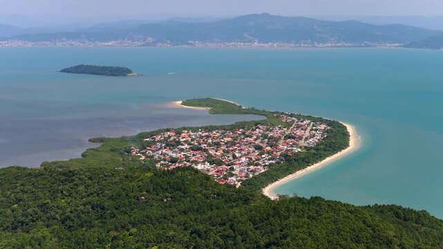 Aerial forward shot of Praia da Daniela in Florianopolis showing peninsula and calm blue sea.