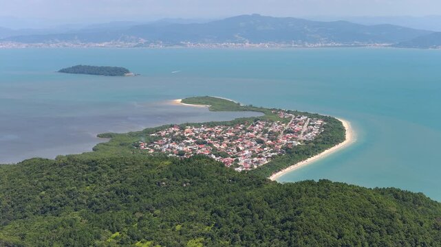 Drone view of Praia da Daniela in Florianopolis with shoreline, calm bay, and anchored boats.