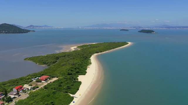 Luxurious waterfront houses surrounded by lush vegetation on the thin peninsula of Praia da Daniela, Florian&oacute;polis. Aerial pullback.