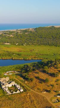 Vertical video. Gelemis, Turkey. Panoramic view of Patara ancient city with gate, road, Hurmalik Hamami at Tepecik, beach and mediterranean sea. Aerial View. Rich colors