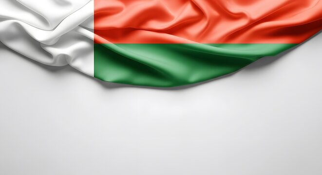 Wavy flag of Madagascar with its red, green, and white colors draped on a plain white background, offering copy space below.