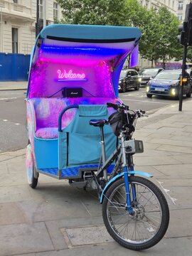 London UK 05.07.2025 Colorful pedicab with neon welcome sign parked on city street vibrant urban transport concept with modern design and evening lights attracting attention
