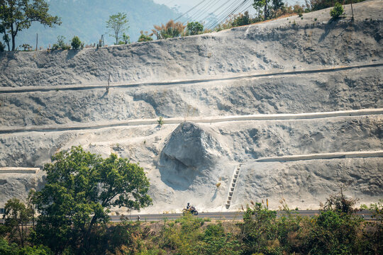 Cliff beside traffic road with working process of geological works for landslide prevention and mountain slope strengthening, soil wall structures construction, protecting landslide prone areas.