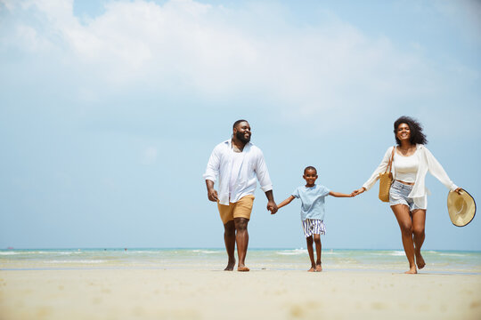 Happy Black Family Holding Hands Walking on Sunny Summer Beach