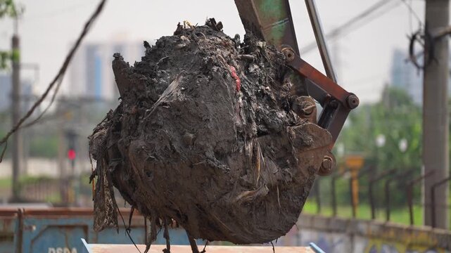 Excavator dredging polluted canal to prevent flooding and improve drainage in urban area