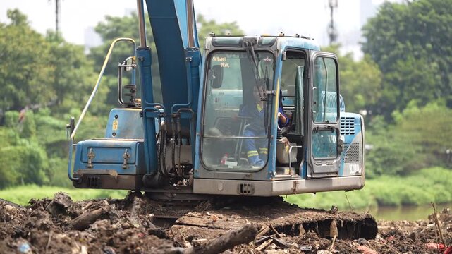 Excavator dredging polluted canal to prevent flooding and improve drainage in urban area
