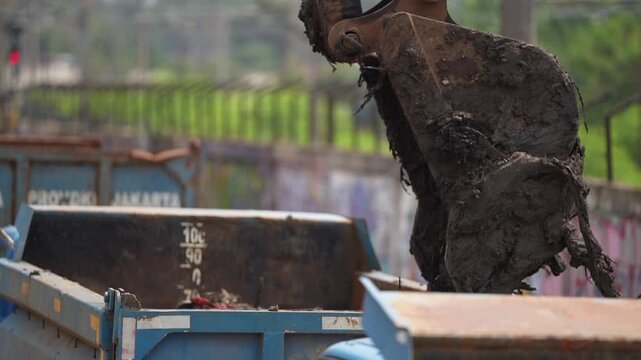 Excavator dredging polluted canal to prevent flooding and improve drainage in urban area