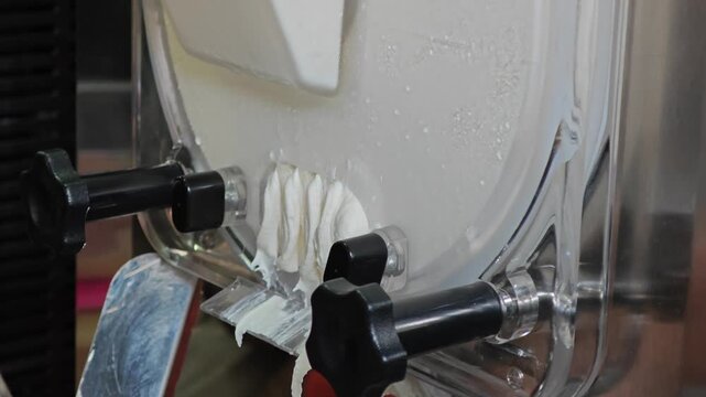 Ice cream maker machine. Ice cream falls into container.