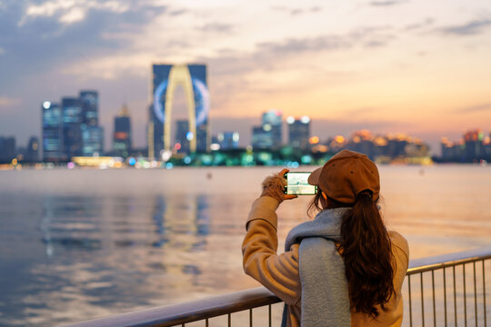 Young woman tourist taking pictures of the landmark building at Jinji Lake in Suzhou, China