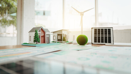 Miniature eco home models with solar panel and wind turbine on a desk, suggesting sustainable architecture, renewable energy planning, and green building design. © Phushutter