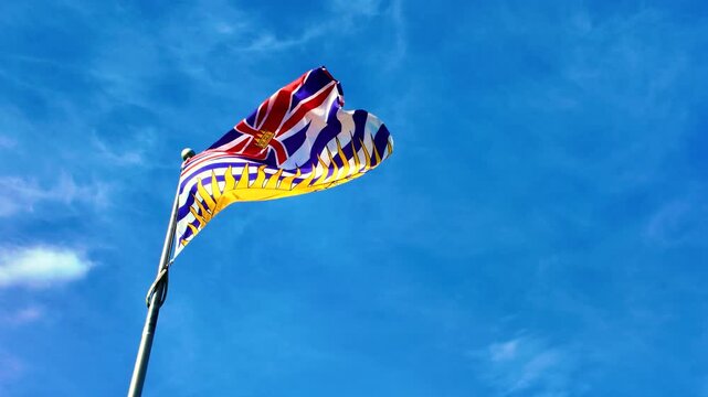 British Columbia provincial flag waving in wind against blue sky