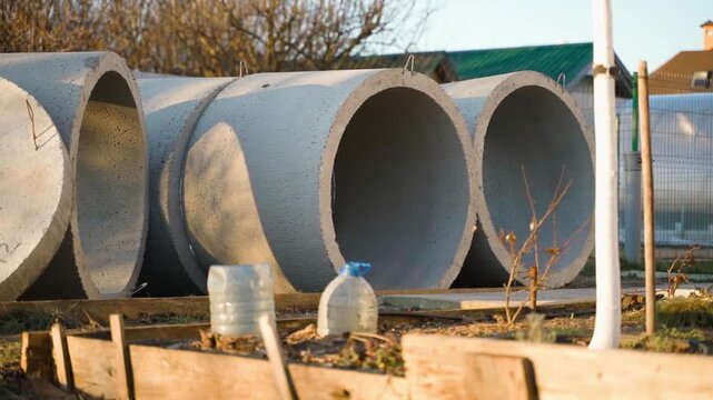 Large concrete sewer pipes stacked outdoors at rural construction storage yard