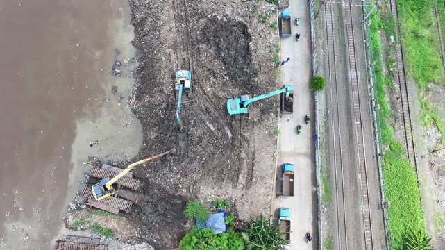 Aerial view The blue and yellow excavator is working to dig and clean the river from mud and rubbish, removing it to the edge of the river middle city