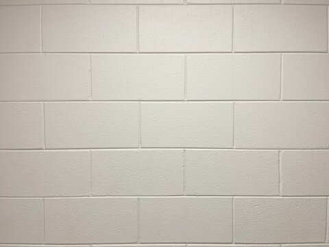 Full frame white painted concrete cinder block wall background texture.