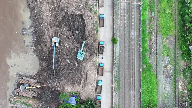 Aerial view The blue and yellow excavator is working to dig and clean the river from mud and rubbish, removing it to the edge of the river middle city